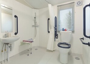 A bathroom with a white sink, a toilet, a shower with a handheld showerhead, and a window with blinds.