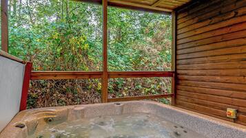 Un bain à remous offrant une vue sur un feuillage dense, encadré par une structure en bois.