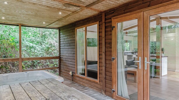 A wooden cabin with a covered porch, sliding glass doors, and a view of the surrounding forest. - 2 bedroom accommodation in Freehay, Cheadle (Freehay, Cheadle)