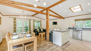 A spacious room with a wooden dining table, a sofa, a kitchen area with a dishwasher, and a ceiling with exposed beams and skylights. - 2 bedroom accommodation in Freehay, Cheadle (Freehay, Cheadle)