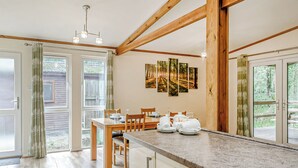 A kitchen with wooden beams, a dining table set for four, and a view of the outdoors through large glass doors. - 2 bedroom accommodation in Freehay, Cheadle (Freehay, Cheadle)