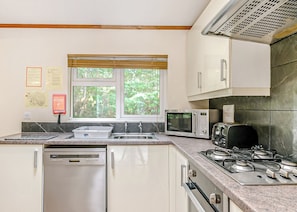 A compact kitchen with a dishwasher, microwave, toaster, and gas stove. - 2 bedroom accommodation in Freehay, Cheadle (Freehay, Cheadle)