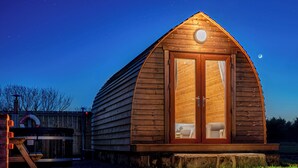 Une cabane en bois avec un toit à deux versants, une véranda et une seule fenêtre visible.