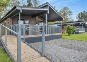 A modern building with a covered porch, a wooden deck, and a gravel driveway.