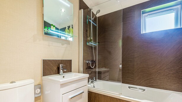 A modern bathroom with a toilet, sink, and bathtub. - 2 bedroom accommodation in Woodhall Spa (Woodhall Spa)