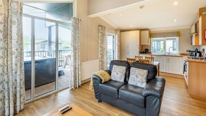 A modern living room with a leather sofa, a dining area, and a kitchen. - 2 bedroom accommodation in Woodhall Spa (Woodhall Spa)