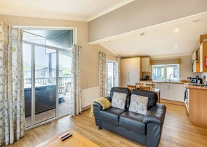 A modern living room with a leather sofa, a dining area, and a kitchen. - 2 bedroom accommodation in Woodhall Spa (Woodhall Spa)