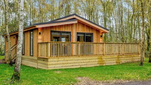 A wooden cabin with a balcony, surrounded by trees. - 1 bedroom accommodation in Haddon (Haddon)