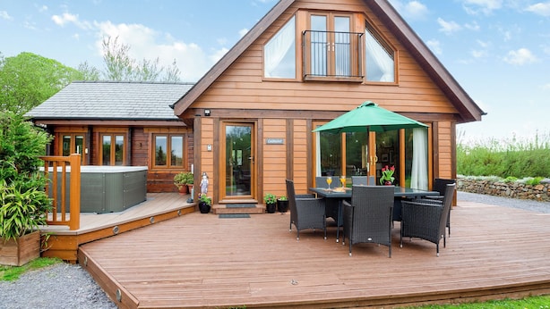 Une cabane en bois dotée d’une terrasse, d’un bain à remous et de meubles de jardin.