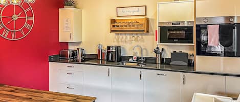 Eine moderne Küche mit roter Akzentwand, Edelstahlgeräten und einem Holzespeise Tisch.