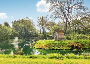 A pond with a wooden structure, surrounded by lush greenery and trees.