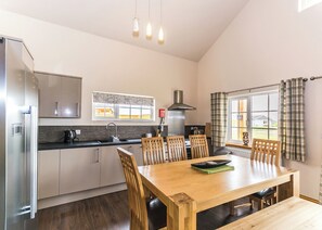A modern kitchen with a dining area, stainless steel appliances, and a large window with curtains.