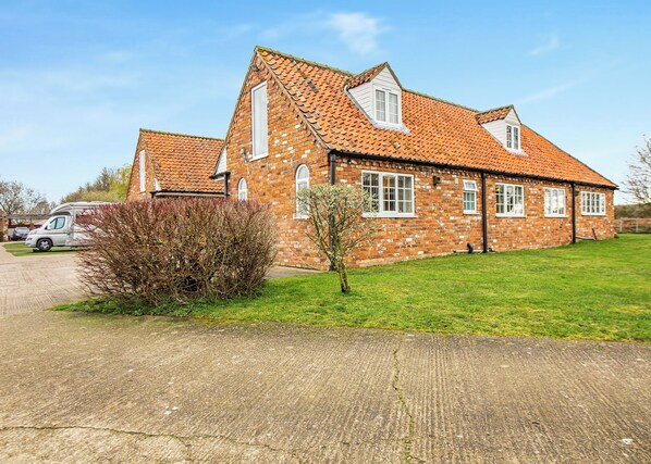 A brick house with a tiled roof, a driveway, and a small tree in the front yard. - Three bedroomed holiday cottage. (Swinethorpe, Nr Lincoln)