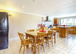A modern kitchen with wooden furniture, a central island, and a view of the outdoors. - Three bedroomed holiday cottage. (Swinethorpe, Nr Lincoln)
