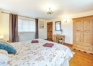 A bedroom with a bed, a desk, a chair, a wardrobe, and a radiator.