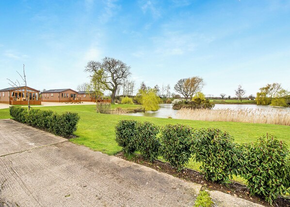 A residential area with a pond, manicured lawns, and a wooden house.