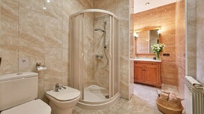 Et moderne badeværelse med en glasafskærmet brusebad, toilet, håndvask og en trækommode med spejl.