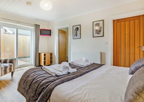A bedroom with a bed, a chair, a wooden cabinet, a radiator, and a wooden door.