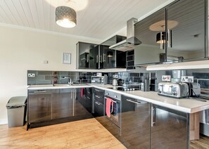A modern kitchen with stainless steel appliances, a large island, and a wooden floor.