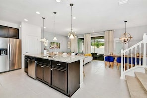 Enjoy meals in the kitchen with a central island and dining area featuring a wooden table and chandelier.