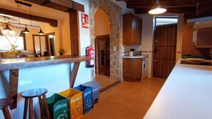 A kitchen with wooden cabinets, a stone archway, and a bar area with stools. - Casa Rural El Ojuelo (VTAR) (El Ojuelo)