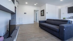 A modern living room with a grey sofa, a flat-screen TV, and a wooden floor. - Vat 52 Sub 16 in Udine (Udine)