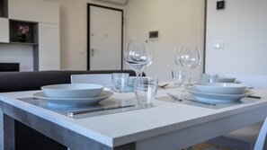 Uma mesa de jantar posta com pratos brancos, copos transparentes e um garfo.