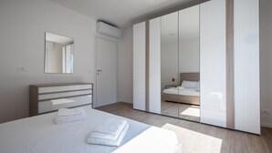 A modern bedroom with a bed, a bedside table, a mirror, and a wardrobe. - Vat 52 Sub 16 in Udine (Udine)