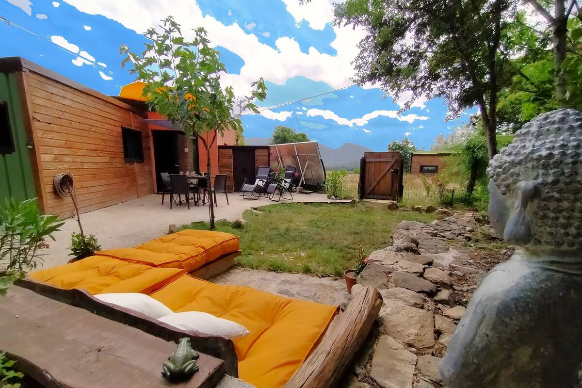 A rustic outdoor seating area with wooden benches and a stone statue.