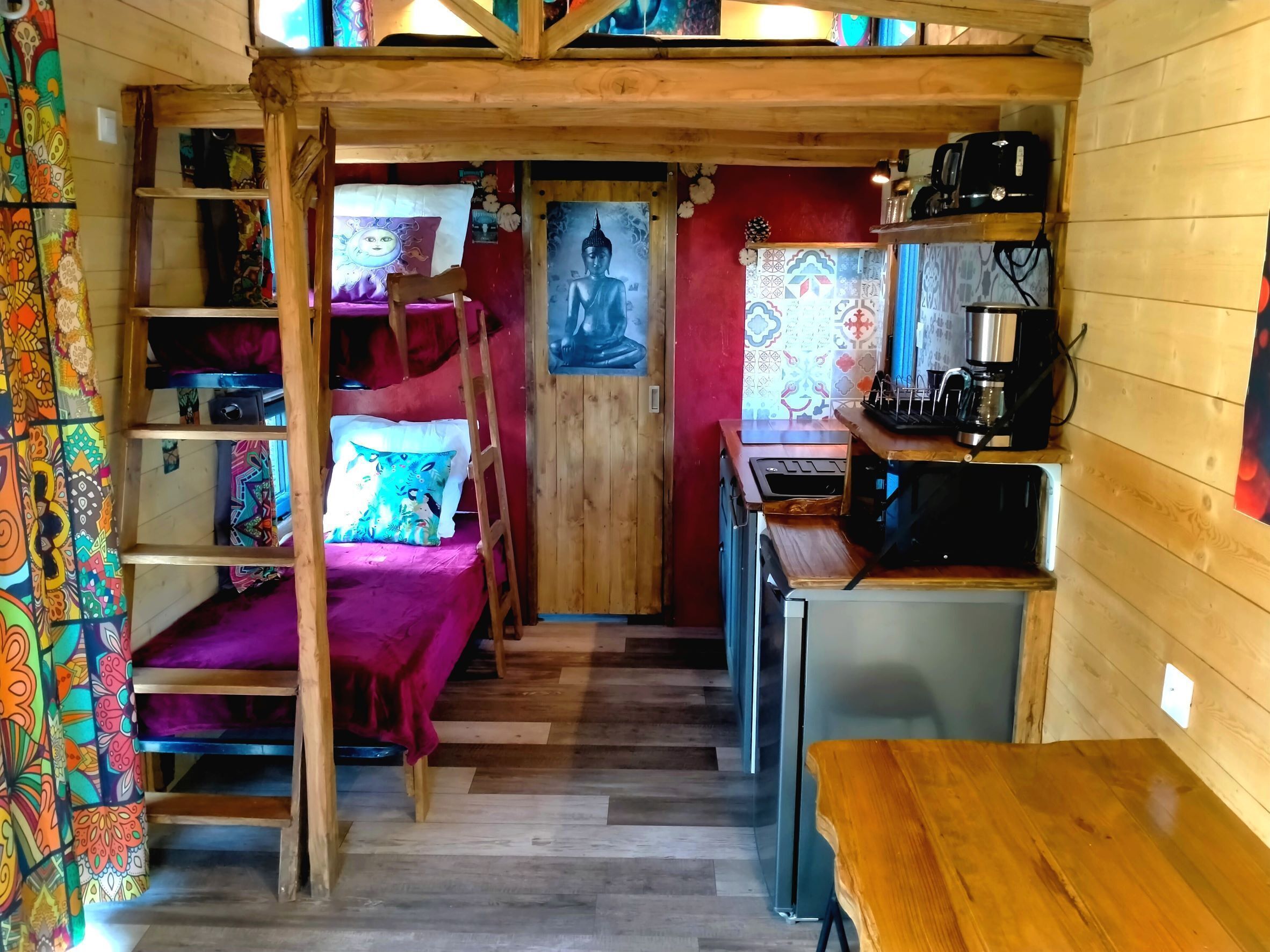 A compact, wooden interior with bunk beds, a kitchenette, and a small dining area.
