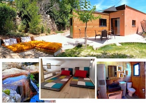 A wooden cabin with a patio, a bed with a yellow cover, a small bathroom, and a view of a natural landscape. - Coeur de Châtaigne (Mons)