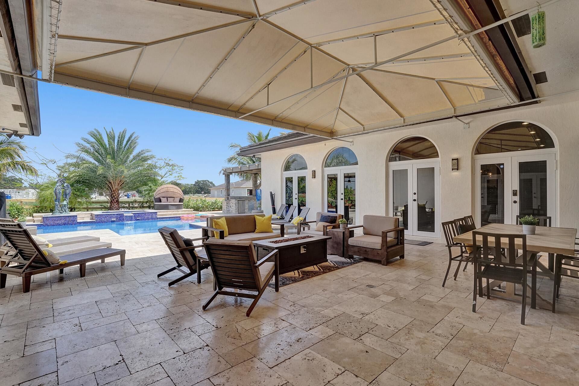 An outdoor patio with a pool, seating areas, and a covered section.