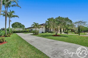 A residential area with a well-maintained lawn, a concrete pathway, and a house with a garage. - 8-BR with Pool & Mini-golf & Soccer (Davie)