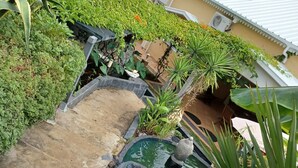 A garden with a water feature, stone steps, and various plants. - La caz à Anne, Villa de Charme (Saint Paul)