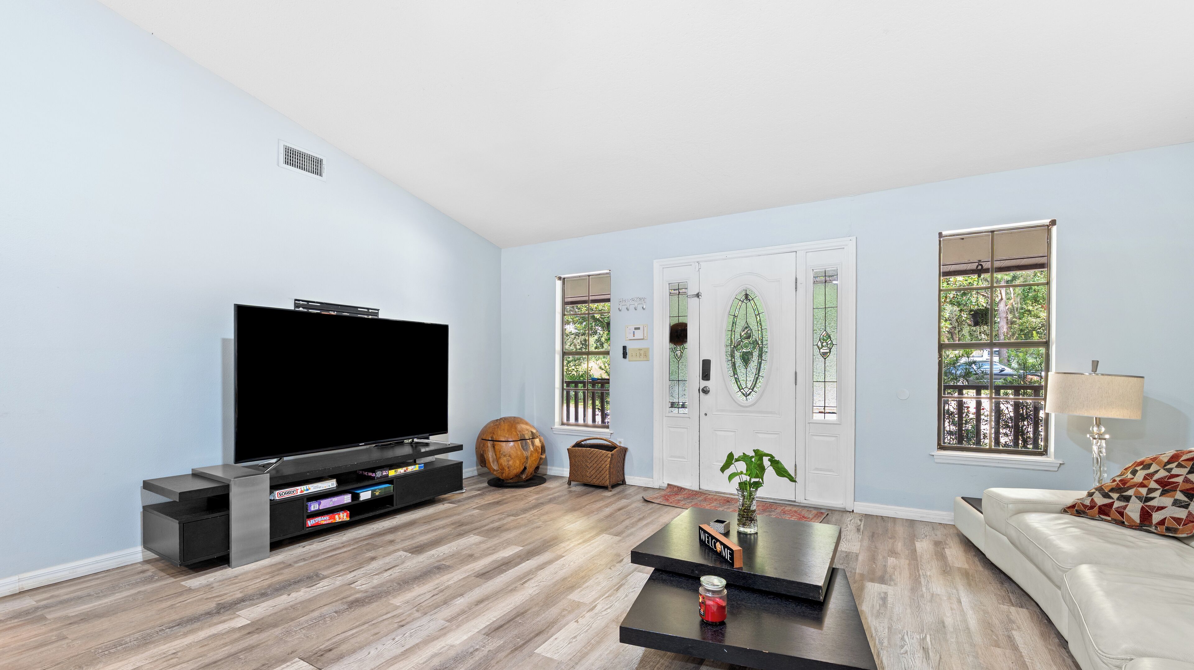 A living room with a flat-screen TV, a sofa, a coffee table, and a door with a glass panel.