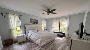 A bedroom with a bed, a desk, a chair, a ceiling fan, and windows with curtains. - Ranch with pool/Lake fishing kayak Paddleboard Soccer Motocross 30 min to Disney (Clermont)