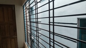 A room with a barred window, a wooden door, and a tiled floor. - Nicely 3 bedrooms apartment at Mohammadpur (Dhaka)