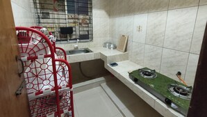 A compact kitchen with a gas stove, a sink, and a window with a metal grill. - Nicely 3 bedrooms apartment at Mohammadpur (Dhaka)