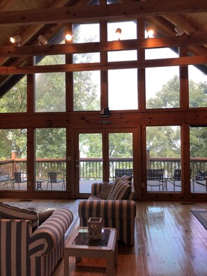 A spacious room with large windows, a wooden ceiling, and a view of the outdoors. - Lakefront Cabin with Dock, Ramp and boat rental (Birchwood)