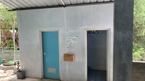 Un petit bâtiment avec une porte bleue et une petite boîte en bois fixée au mur.