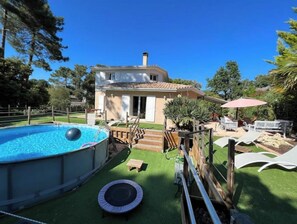 Ein Haus mit Schwimmbad, Trampolin und einer Terrasse mit Gartenmöbeln.