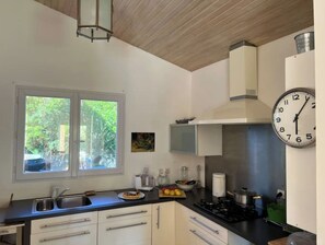 A kitchen with a window, a clock, and a stove. - Villa sur le Golf Entre Océan et lac (Lacanau)