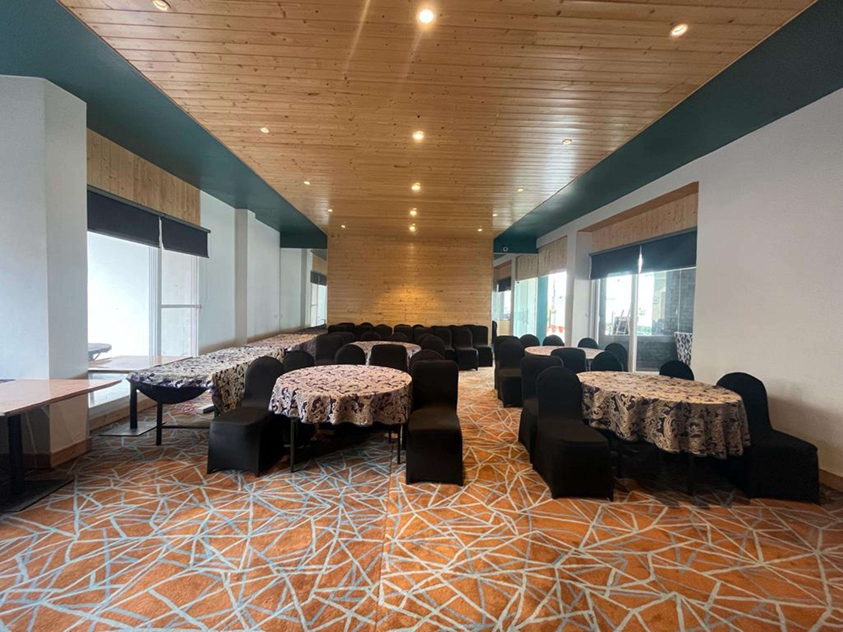 A conference room with round tables, chairs, and a patterned carpet.