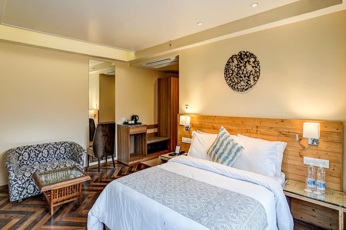 Una habitación de hotel con una cama grande, un sofá, un escritorio y una obra de arte colgada en la pared.