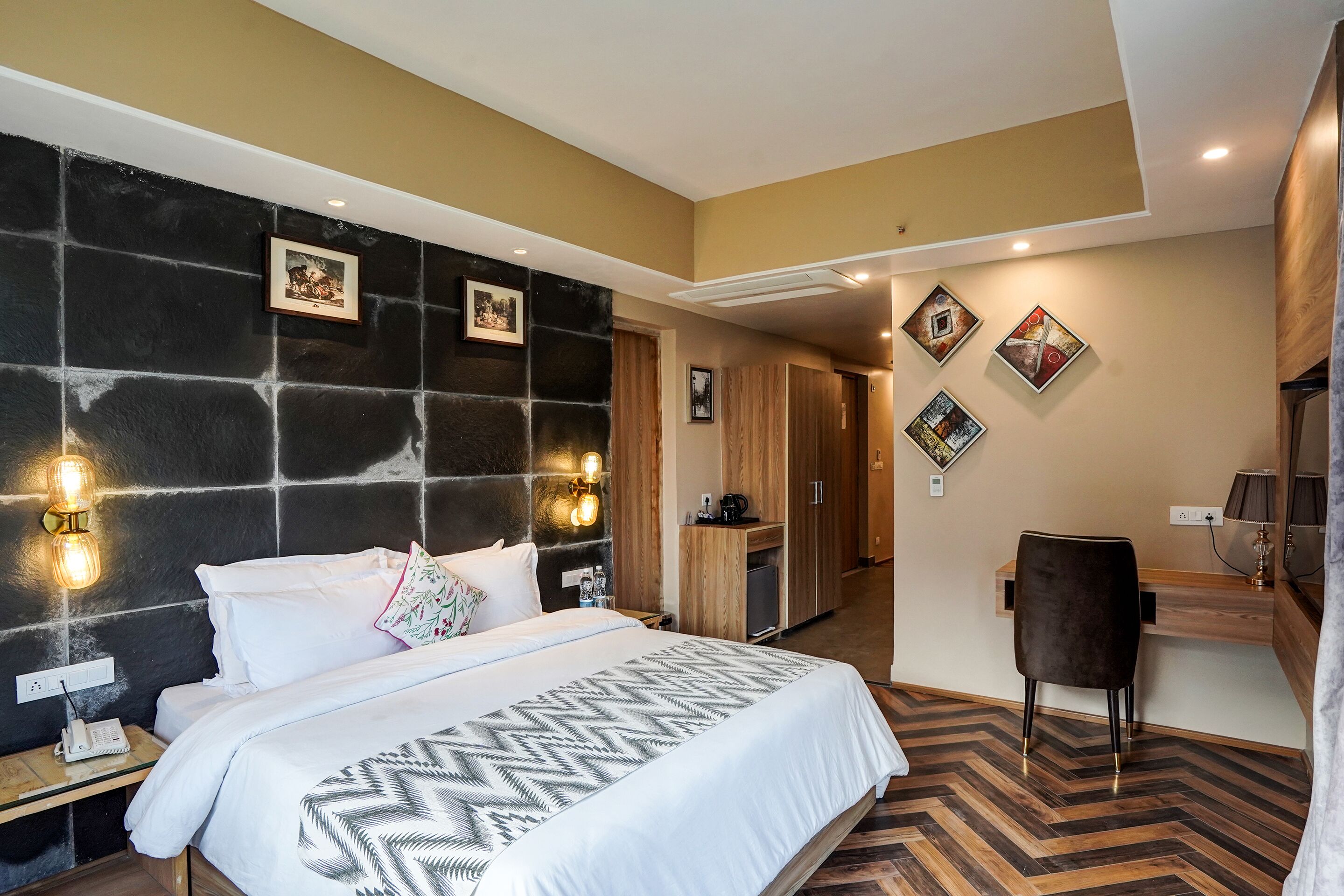 A modern hotel room with a large bed, a desk, and a wardrobe.