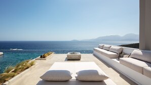 Un espace extérieur moderne, aménagé pour se détendre, avec vue sur la mer et les montagnes.