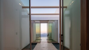 Un couloir moderne avec des portes vitrées donnant sur un balcon offrant une vue sur la mer.