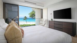 A modern bedroom with a large bed, a TV mounted on the wall, and a view of the beach. - Hapuna Beach Residences A34 Two Bedroom (Kamuela)
