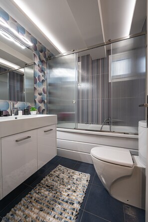 A modern bathroom with a bathtub, toilet, and vanity.