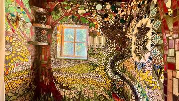 Une pièce avec un mur décoré de mosaïques, une fenêtre et une petite étagère.